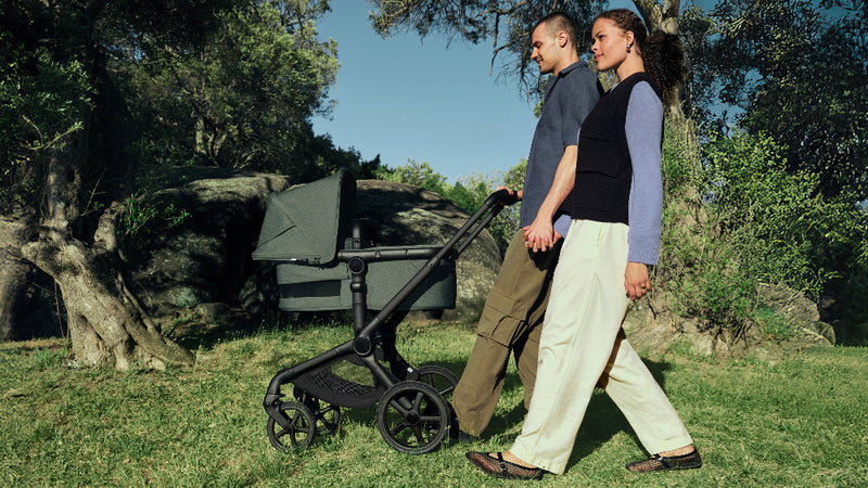 Two people walking with a stroller in a park setting